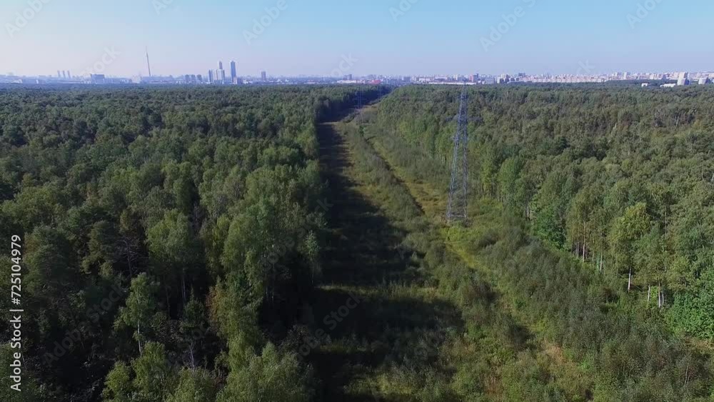 Townscape on horizon and electric power line among forest Townscape on horizon and electric power line among forest