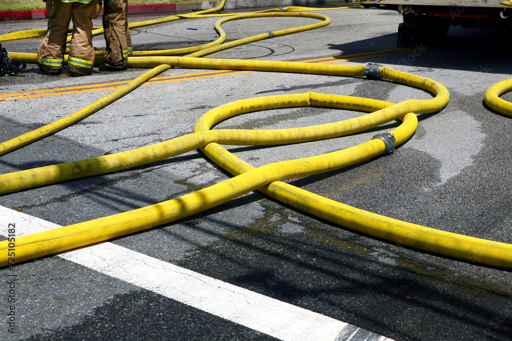 Horizontal photo of a tangle of yellow fire hoses on a wet city street. Horizontal photo of a tangle of yellow fire hoses on a wet city street.