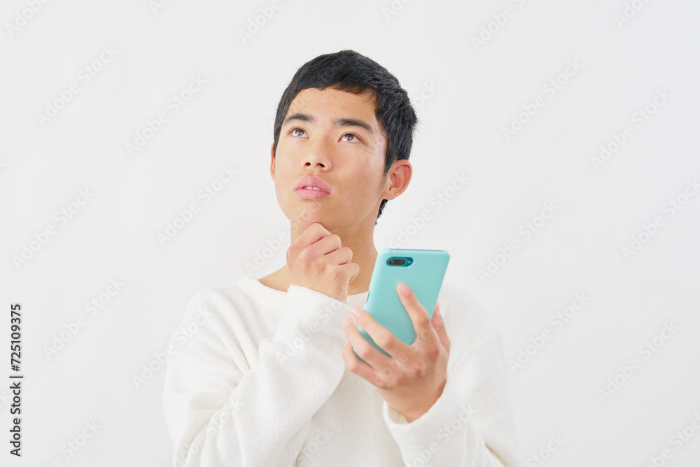 スマートフォンを持って考える男の子 白背景 スマートフォンを持って考える男の子 白背景