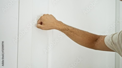 Close-up of a male hand knocking on a white door inside a bright home. photo