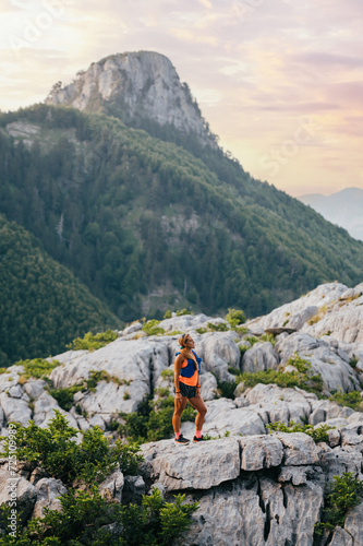 An extreme skyrunner is standing on mountain cliff and enjoying the view. photo