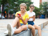 Teenagers share information with each other from smartphones while relaxing on the street