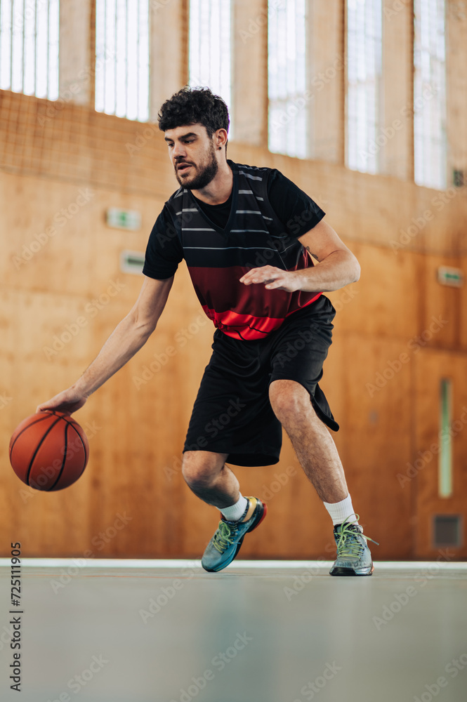 A fit professional basketball player in action dribbling a ball on court. A fit professional basketball player in action dribbling a ball on court.
