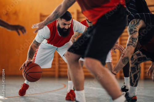 Tattooed basketball player is dribbling a ball in crowd on court.