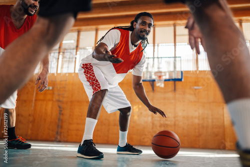 Tableau sur toile Interracial basketball player is dribbling ball while practicing with team