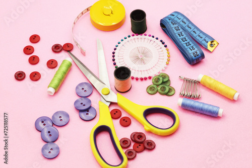 Sewing accessories background. Tailor shop texture. Measuring tape, scissors, buttons flat lay. Top view collection. Sewing kit isolated on pink fabric.