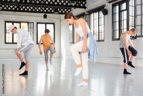 Teenage girl and boys having dance training in studio, performing contemporary dance elements