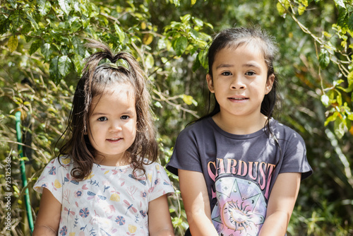 Close up image of two young Maori sisters posing for their photograph to be taken outside in a nature setting.