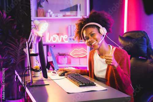 African American girl gaming streamer team winner playing online fighting with Esport wearing headphones in neon lighting room. Talking other players planing strategies to win competitors. Tastemaker.