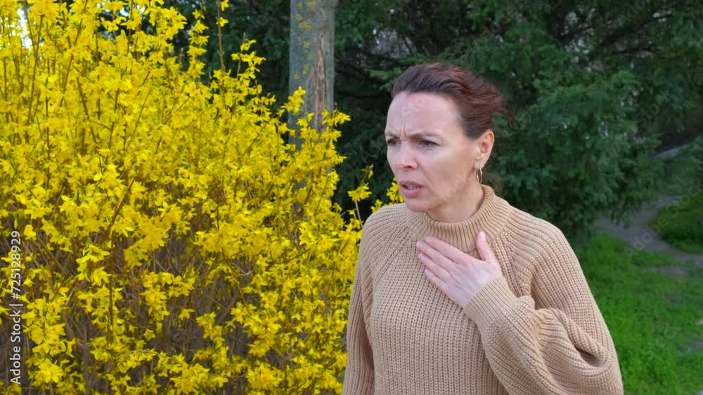 Feel spring pollen allergy outdoor. A woman feel discomfort and use an inhaler by the yellow blooming tree in the spring park. A concept of seasonal allergy problems. Feel spring pollen allergy outdoor. A woman feel discomfort and use an inhaler by the yellow blooming tree in the spring park. A concept of seasonal allergy problems.