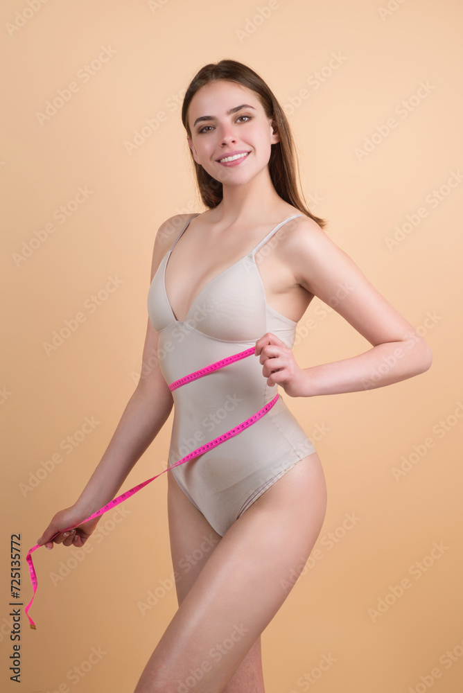 Happy woman holding apple wrapped with measuring tape on waist. Weight loss concept. Dieting and waist exercise. Woman measuring waistline. Fit Girl measuring waist. Sport model measuring waistline. Happy woman holding apple wrapped with measuring tape on waist. Weight loss concept. Dieting and waist exercise. Woman measuring waistline. Fit Girl measuring waist. Sport model measuring waistline.