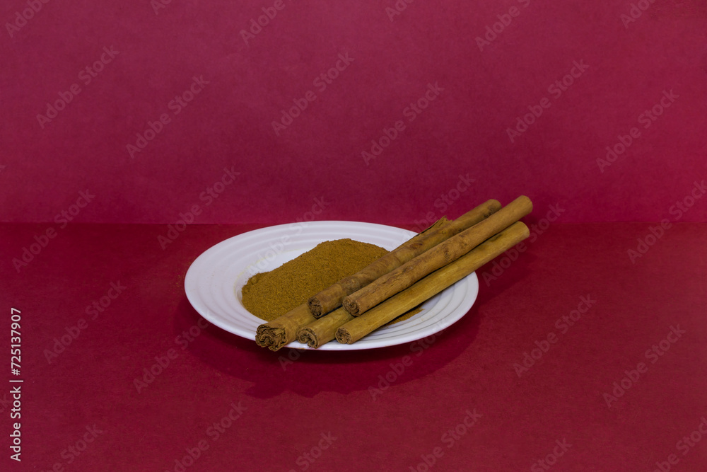 Cinnamon sticks next to ground cinnamon on saucer in beautiful details