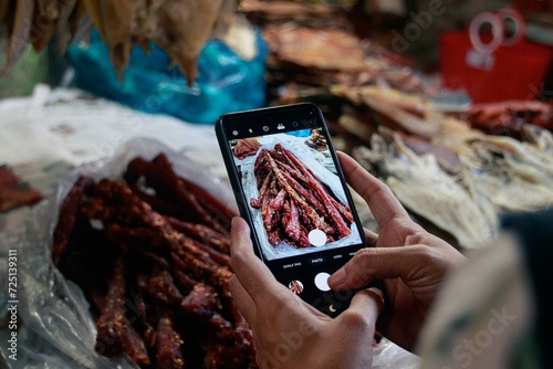 Capturing an image of traditional cambodian beef jerky called sach ko ngeat at the local Samaki Market with a smartphone. Kampot, Cambodia, Asia photo