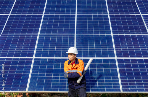 Confident male professional engineer working installing large solar panel system. Standing with arms crossed and looking away. Alternative energy technician work for the future.