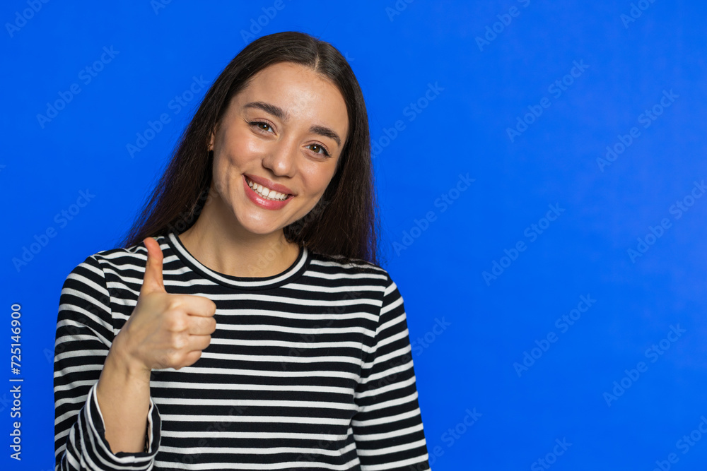 Like. Caucasian woman raises thumbs up agrees with something or gives positive reply recommends advertisement likes good idea feedback celebrating success victory. Girl on blue background. Copy-space Like. Caucasian woman raises thumbs up agrees with something or gives positive reply recommends advertisement likes good idea feedback celebrating success victory. Girl on blue background. Copy-space