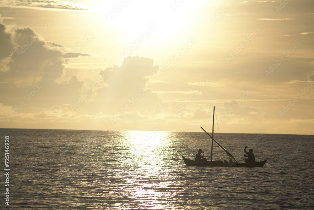 Silo of a small wooden canoe on the ocean at sunset