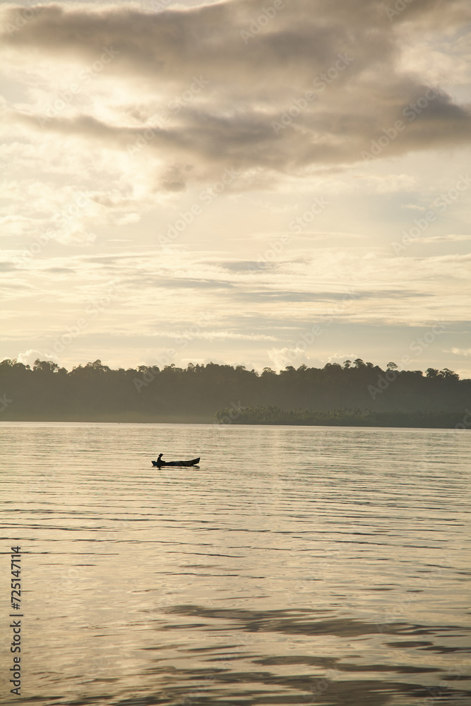 Silo of a small wooden canoe on the ocean at sunset Silo of a small wooden canoe on the ocean at sunset