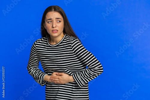 Sick ill woman in striped blouse suffering from period cramps, painful stomach ache. Girl holding belly feeling abdominal or menstrual pain. Abdominal pain gastritis diarrhea indigestion. Copy-space