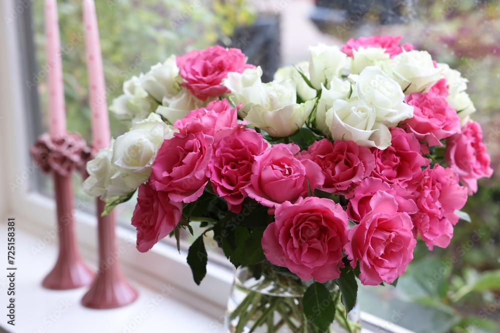 Vase with beautiful bouquet of roses and candles on windowsill indoors, closeup Vase with beautiful bouquet of roses and candles on windowsill indoors, closeup