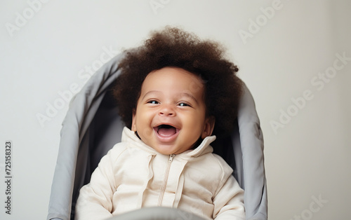 Happy afro newborn in the stoller at the pastel background. photo