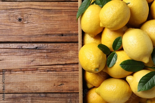 Fresh lemons in crate on wooden table  top view. Space for text