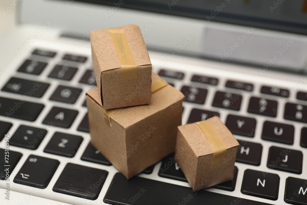 Internet shopping. Small cardboard boxes on laptop, closeup