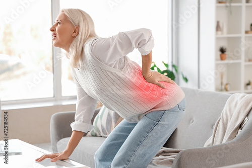 Mature woman feeling pain in spine at home photo