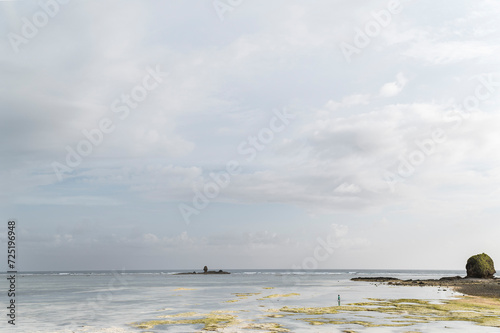 Indonesian fisherman collecting mollusks on the  reef at low tide, Lombok, Indonesia photo