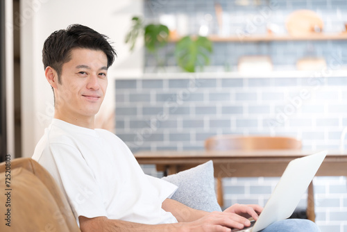 カフェや自宅ででパソコンを使うアジア人（日本人）のハンサムな中年男性　カメラ目線 春夏のイメージ