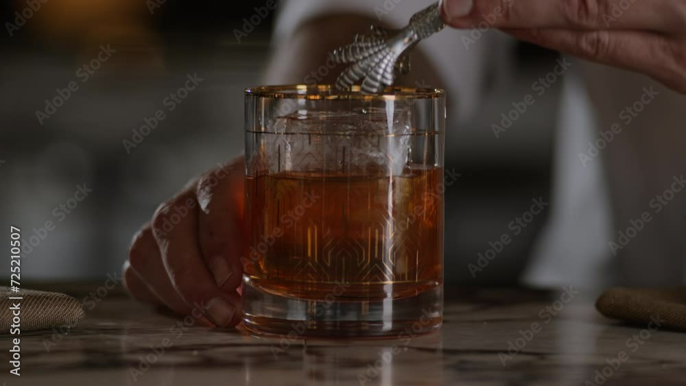 Gently placing an ice cube into an old fashioned Gently placing an ice cube into an old fashioned