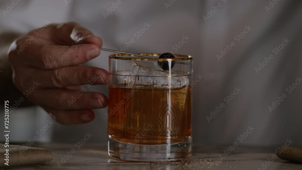 Bartender garnishes an old fashioned with a maraschino cherry Bartender garnishes an old fashioned with a maraschino cherry