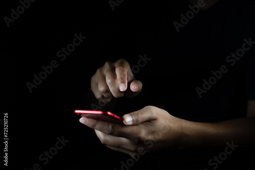 Male hands using a smartphone or tablet in a dark room. Holding hands. Black background. Home office. For work. for social media or looking for information