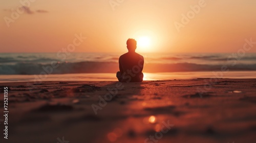 A man sitting lonely on the beach watching a beautiful sunset.