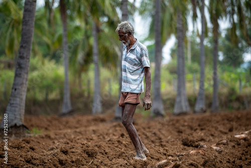 In the field, an Indian farmer is doing farming work.