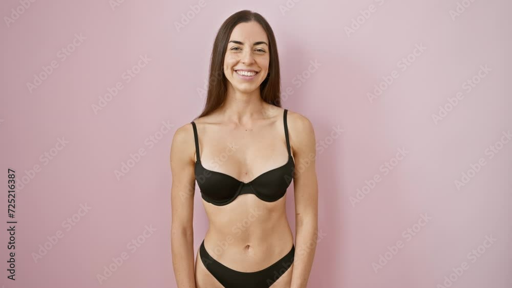 Radiant young hispanic woman in beautiful lingerie, flaunting a positive, confidence-laden smile with gleaming teeth over an isolated pink background Radiant young hispanic woman in beautiful lingerie, flaunting a positive, confidence-laden smile with gleaming teeth over an isolated pink background