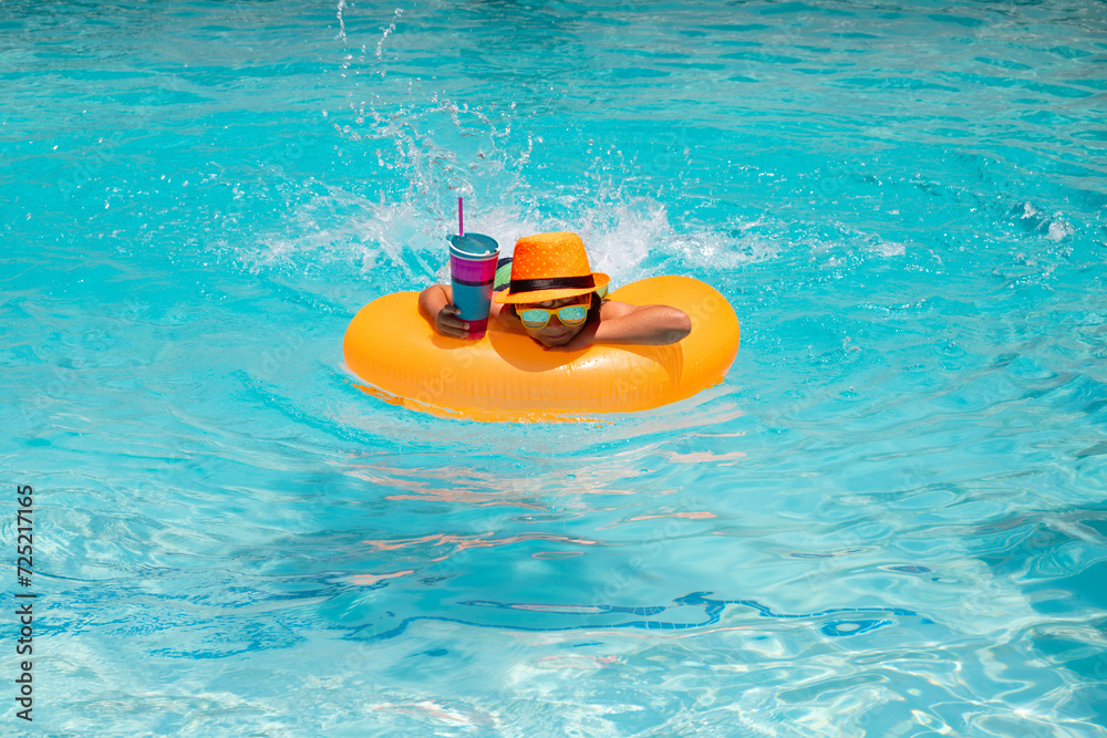 Fototapeta premium Kids summer relax. Kid boy in swim pool swimming on inflatable ring. Kid swim with orange float. Water toy, healthy outdoor sport activity for children. Kids beach fun. Fashion summer kids hat.
