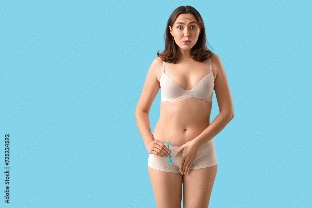 Naklejka premium Beautiful young shocked woman with razor on blue background