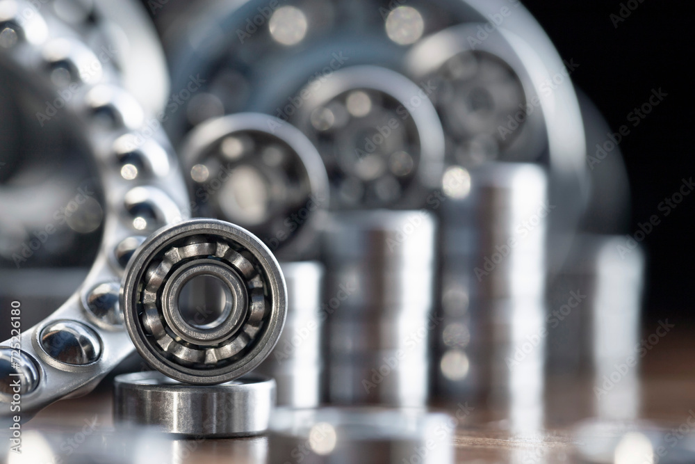 Metal radial ball bearings for mechanical engineering, machine tools and large equipment in the form of a diagram rising up on a blurred glare background of metal products in macro with copy space. Metal radial ball bearings for mechanical engineering, machine tools and large equipment in the form of a diagram rising up on a blurred glare background of metal products in macro with copy space.