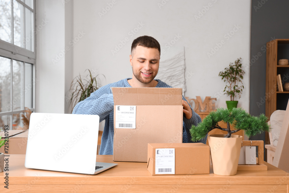 Young man unpacking parcel on table at home Young man unpacking parcel on table at home