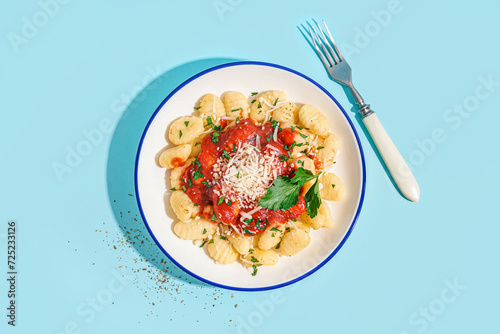 Canvas Print Plate of tasty gnocchi with tomato sauce and cheese on blue background