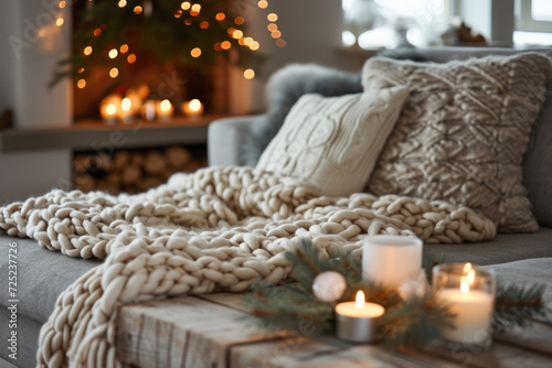 Cozy winter living room interior with knitted blanket and festive candles. Home comfort and holiday season.