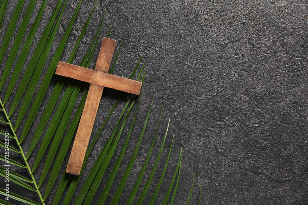 Wooden cross and palm leaf on black background