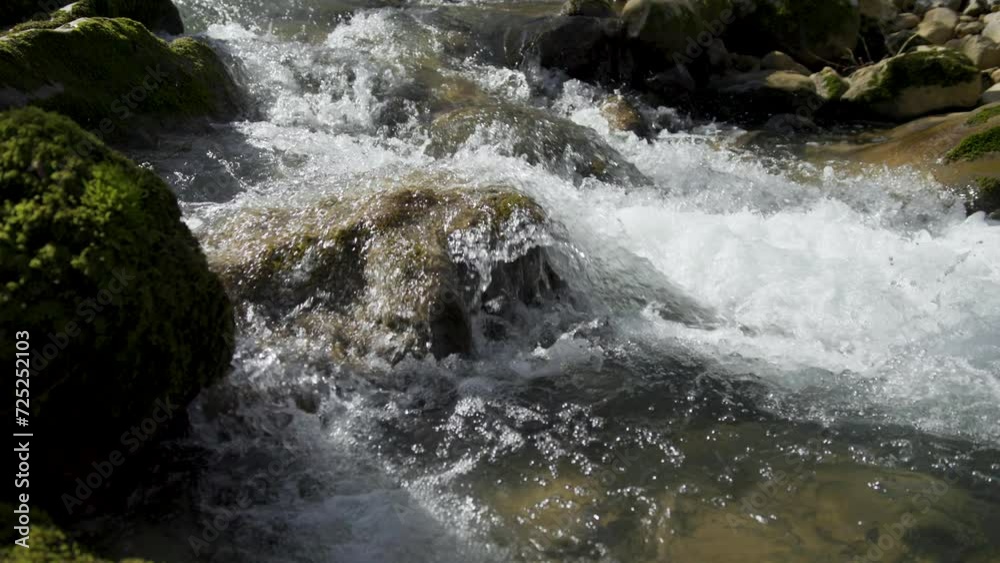 The water of the forest stream flows through the mossy rocks. Slow motion. The water of the forest stream flows through the mossy rocks. Slow motion.