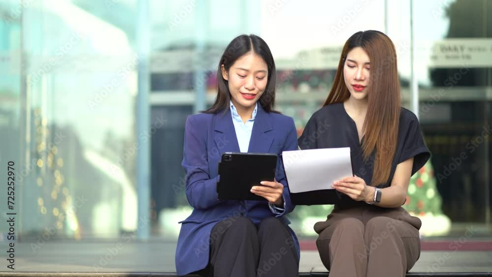 Asian business team sitting in the city using a cellphone and tablet. Asian business team sitting in the city using a cellphone and tablet.