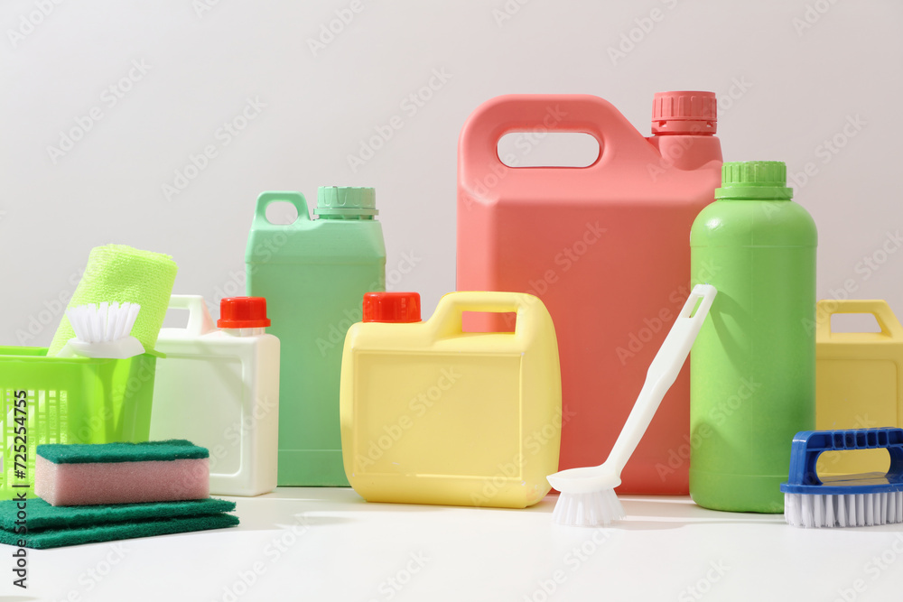 Front view of different bottle and canisters mockup of detergent product displayed on white background with cleaning tools. Housework and professional cleaning service supplies.