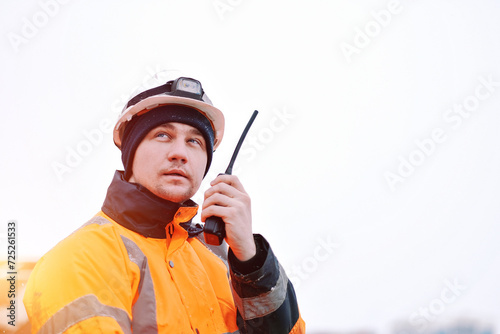 An Offshore Foreman With A Portable Radio Station In The Hand. Seafarer Communicating Using A VHF Radio Station. Communication At Sea During Distress. Project Manager Supervising The Ongoing Loading.	