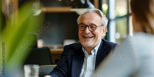Elderly businessman smiling during a casual meeting in a contemporary cafe setting. expressive portrait, lifestyle imagery. AI
