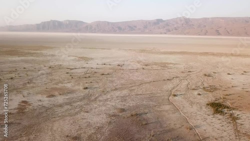 Landing in salt lake desert in mountain foothill rural countryside the wide panoramic view of drought climate dry landscape hot summer hazy day in Iran poverty agriculture concept farm land fig tree photo