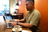 Asian man working with laptop in coffee shop. Copy space.