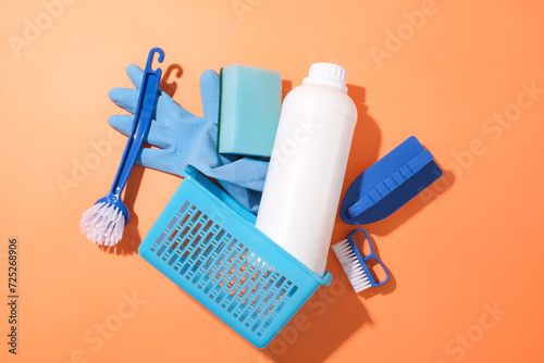 Various cleaning items Includes: brush, rubber gloves detergent bottle and plastic baskets on red background. Advertising mockup for cleaning products. Top views. Copy space.